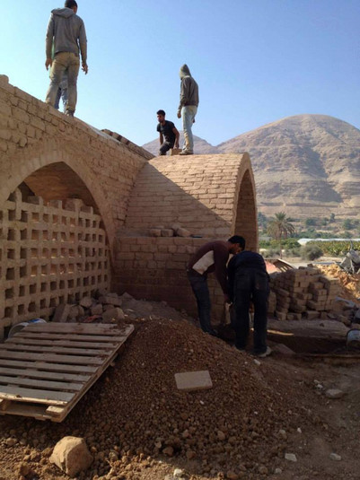 eople constructing an arched brick structure in a rural, mountainous area