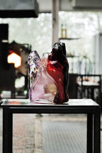 Colored glass sculpture displayed on a table in a studio.