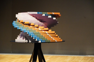 Stak af 10 Principles to Build On arrangeret som en spiralformet skulptur på et rundt bord.