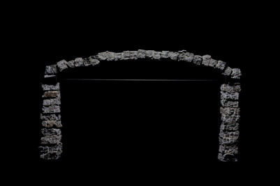 Arched structure of small concrete blocks supported by two vertical columns.