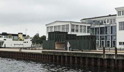 Mørkegrøn træpavillon på kajkant