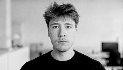 Black-and-white portrait of a young person with short hair and a dark sweater.