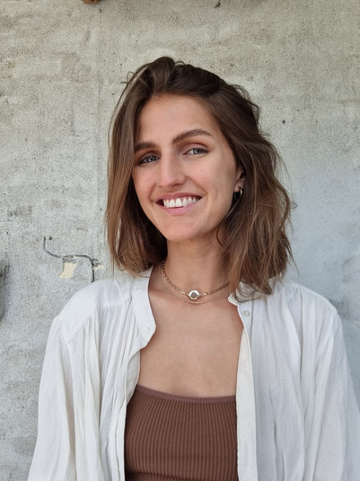 Portrait of a smiling woman in front of a concrete wall.
