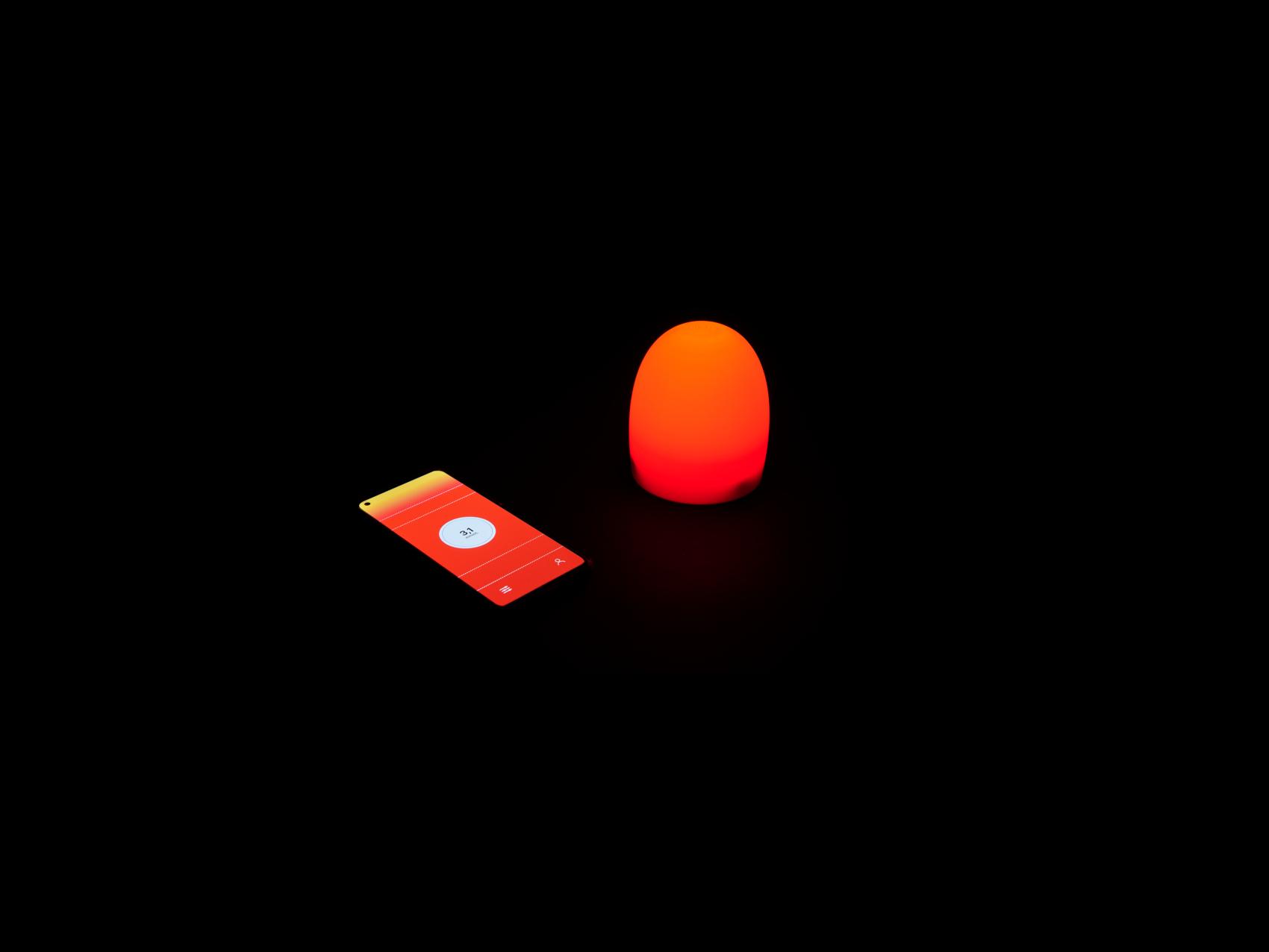 The image shows a smartphone with a red-lit screen displaying low blood sugar levels at 3,1 mmol, placed next to a small, glowing red lamp, both in a dark environment
