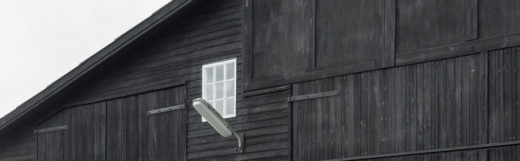 Sort træbygning med hvide vinduer og udendørs lampe.