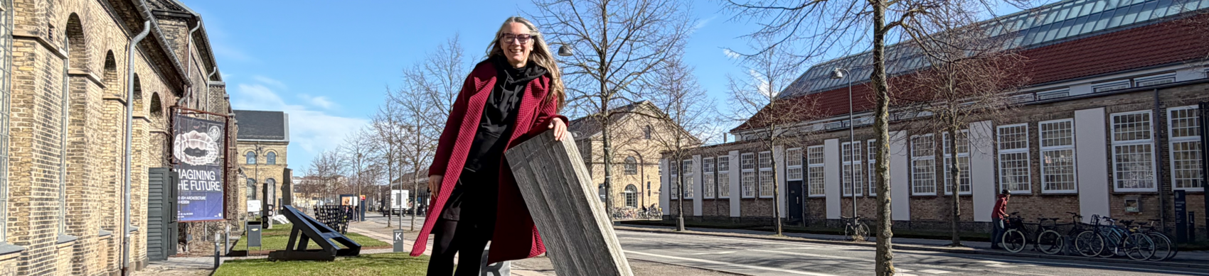 Person står på T-formet skulptur på gade i solskin
