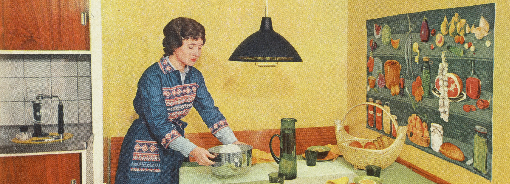 Kvinde dækker et spisebord i et farverigt køkken med gule vægge.