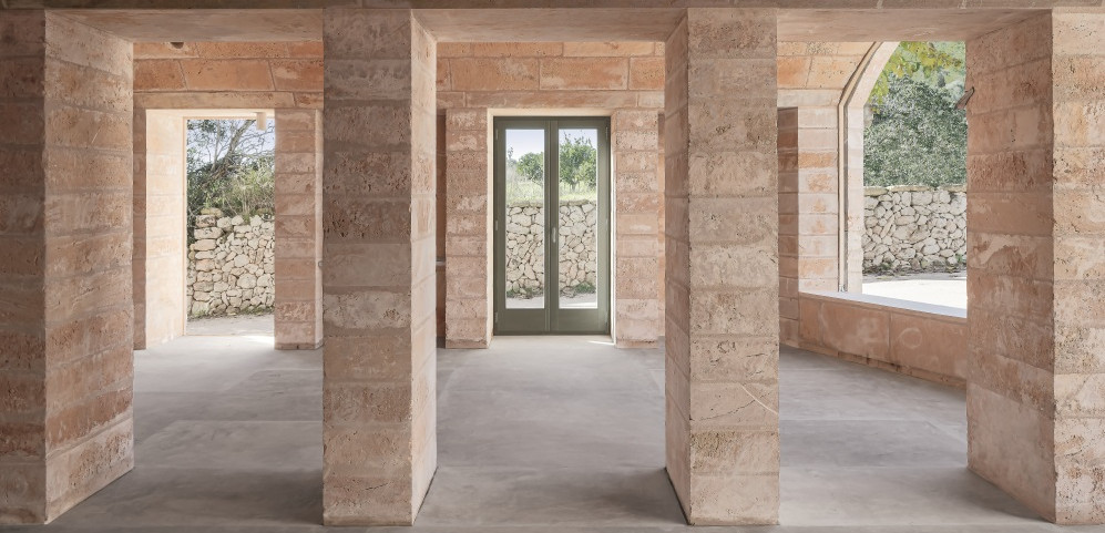Raw interior with stone walls, columns and large openings to the garden.